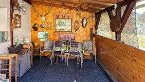 Ein gemütliches Blockhauss-Interieur mit Holzwänden, einem Essbereich mit floralen Stühlen und verschiedenen Jagdtrophäen an den Wänden.