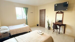 Een hotelkamer met twee bedden, een televisie, een bureau en een potplant.