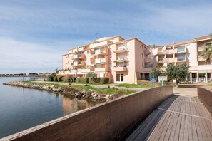 A waterfront apartment complex with balconies, a wooden boardwalk, and a calm body of water. - AS27106-P2 ground floor, pool parking, air conditioning and wifi (LE GRAU DU ROI)