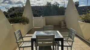 An outdoor patio with a table and chairs, surrounded by walls and a view of the cityscape. - ENSO - Studio Héliopolis J 4 + garage - Luxe - 2 people (AGDE)
