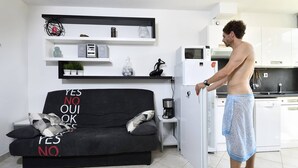 A modern living room with a black sofa, a coffee machine, and a refrigerator. - ENSO - Studio Héliopolis J 4 + garage - Luxe - 2 people (AGDE)