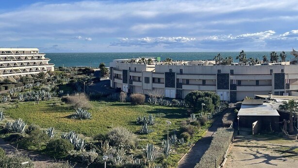 A coastal hotel with multiple buildings, a landscaped garden, and a clear view of the sea. - Apartment Héliopolis J 42 - 5 people (AGDE)