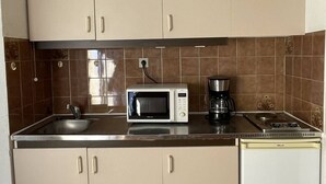 A compact kitchen with beige cabinets, a microwave, a coffee maker, and a refrigerator. - Apartment Héliopolis J 42 - 5 people (AGDE)