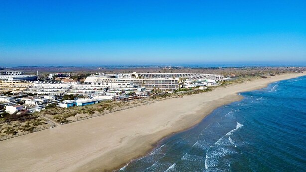 An aerial view of a coastal hotel with multiple buildings, a sandy beach, and the ocean. - CAP FACTORY - Studio Héliopolis K 1 with garage - Luxe - 2 people (AGDE)