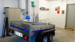 A utility trailer with a license plate in a room with white walls, a water heater, and various cleaning supplies. - CAP FACTORY - Studio Héliopolis K 1 with garage - Luxe - 2 people (AGDE)