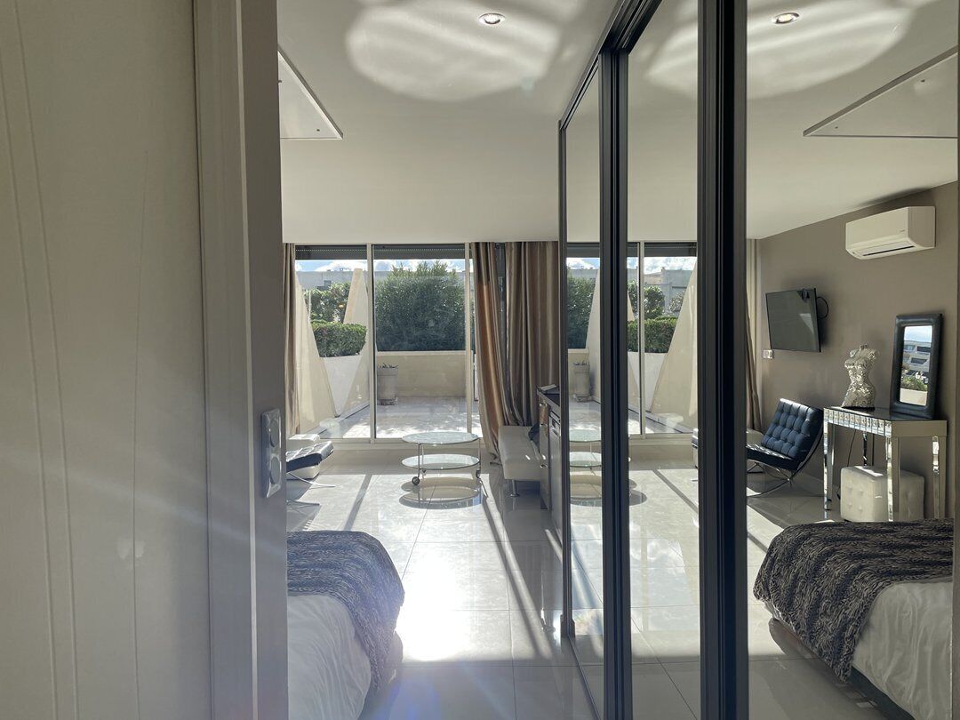 A modern hotel room with a balcony, a bed, a desk, and a chair.