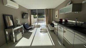 A modern kitchen with a dining area, a sofa, and a TV. - KERYLOS - Studio Héliopolis K 3 with garage - Luxe - 2 people (AGDE)