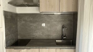 Une cuisine compacte avec des meubles en bois, une hotte en acier inoxydable, un évier et un plan de travail.