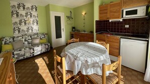 Ein gemütlicher Wohnraum mit Essbereich, Küchenzeile und einer Couch mit gemusterten Kissen.