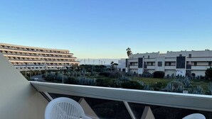 Eine Terrasse mit einem runden Tisch und vier Stühlen, mit Blick auf eine Parkgarage und Gebäude.