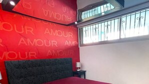 A bedroom with a large bed, a nightstand, a lamp, and a window with decorative bars. - AMOUR AMOUR - Apartment Héliopolis K 209 - Luxe - 4 people (AGDE)