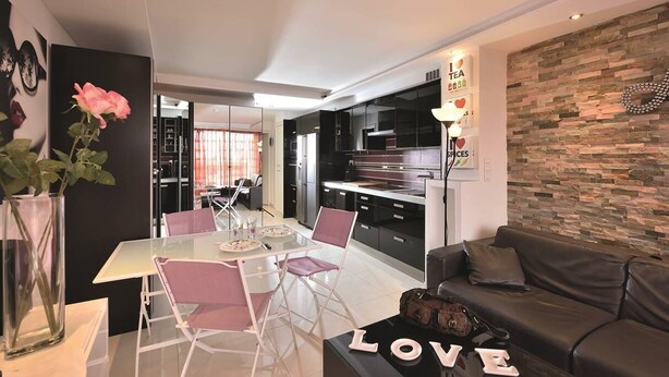 A modern living room with a glass dining table, a sofa, and a decorative vase with a rose. - AMOUR AMOUR - Apartment Héliopolis K 209 - Luxe - 4 people (AGDE)