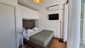 Een slaapkamer met een bed, een ventilator, een tv aan de muur en een airconditioning.