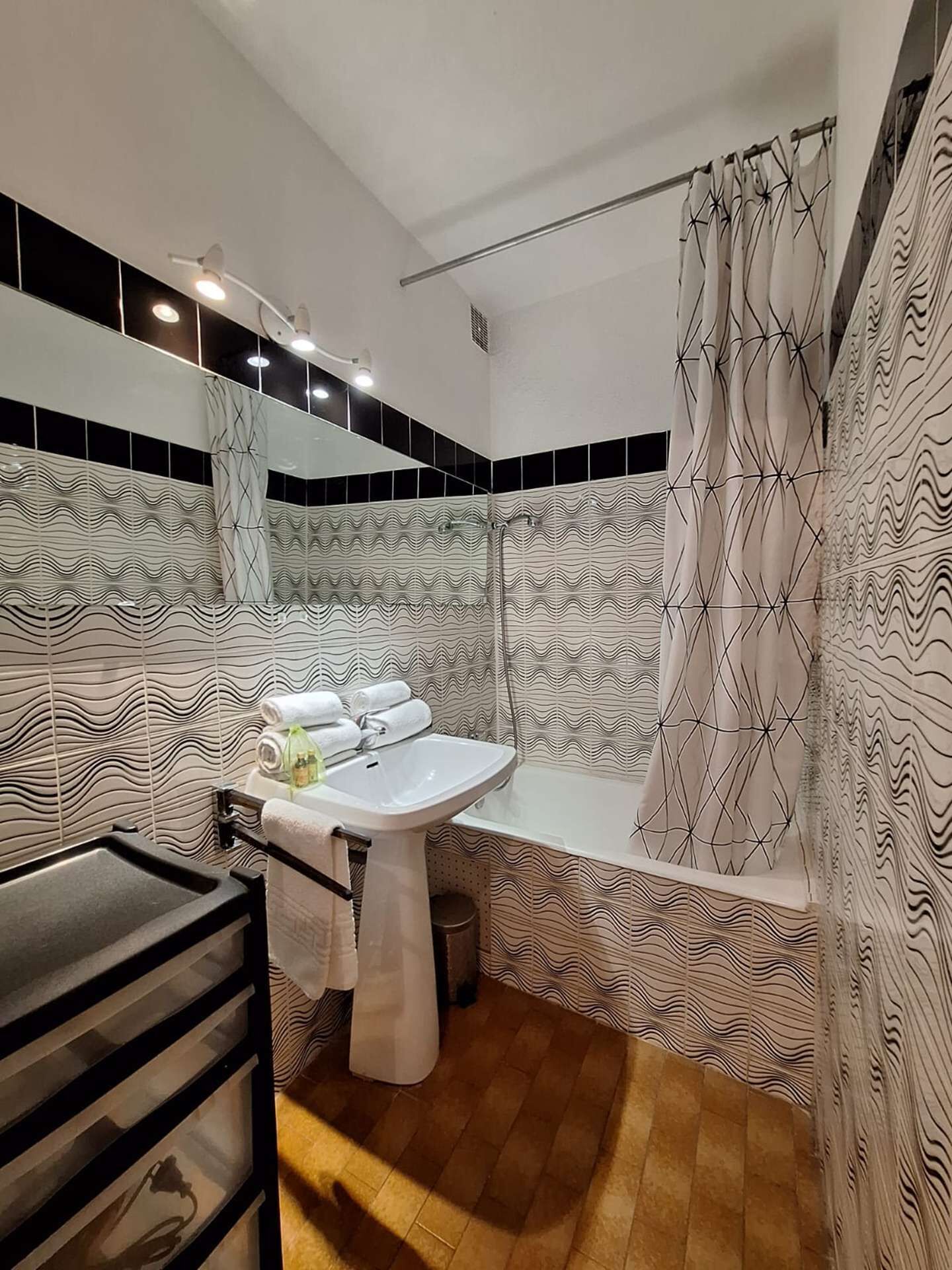 A bathroom with a white sink, a bathtub, and a shower area. There are towels and toiletries on the sink.