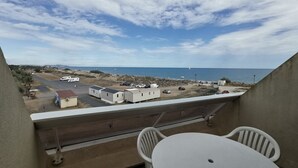 A balcony with a table and chairs, overlooking a beach with mobile homes and a clear sky. - Studio Héliopolis L 20 - 2 people (AGDE)