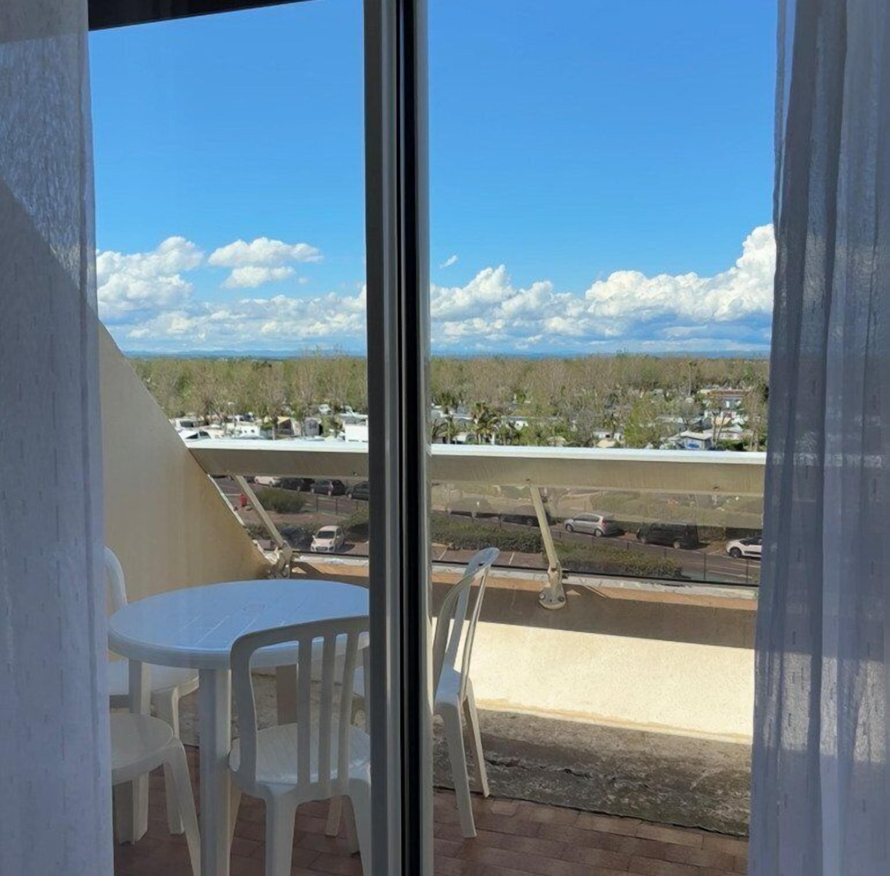 Un balcón con vista a una zona residencial, una mesa y dos sillas.