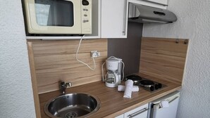 A compact kitchenette with a microwave, coffee maker, sink, and a small refrigerator. - Studio Héliopolis L 20 - 2 people (AGDE)