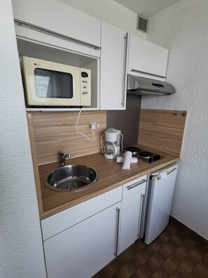A compact kitchenette with a microwave, coffee maker, sink, and a small refrigerator. - Studio Héliopolis L 20 - 2 people (AGDE)