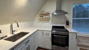 Une cuisine moderne avec des meubles blancs, une cuisinière en acier inoxydable et un four encastré.