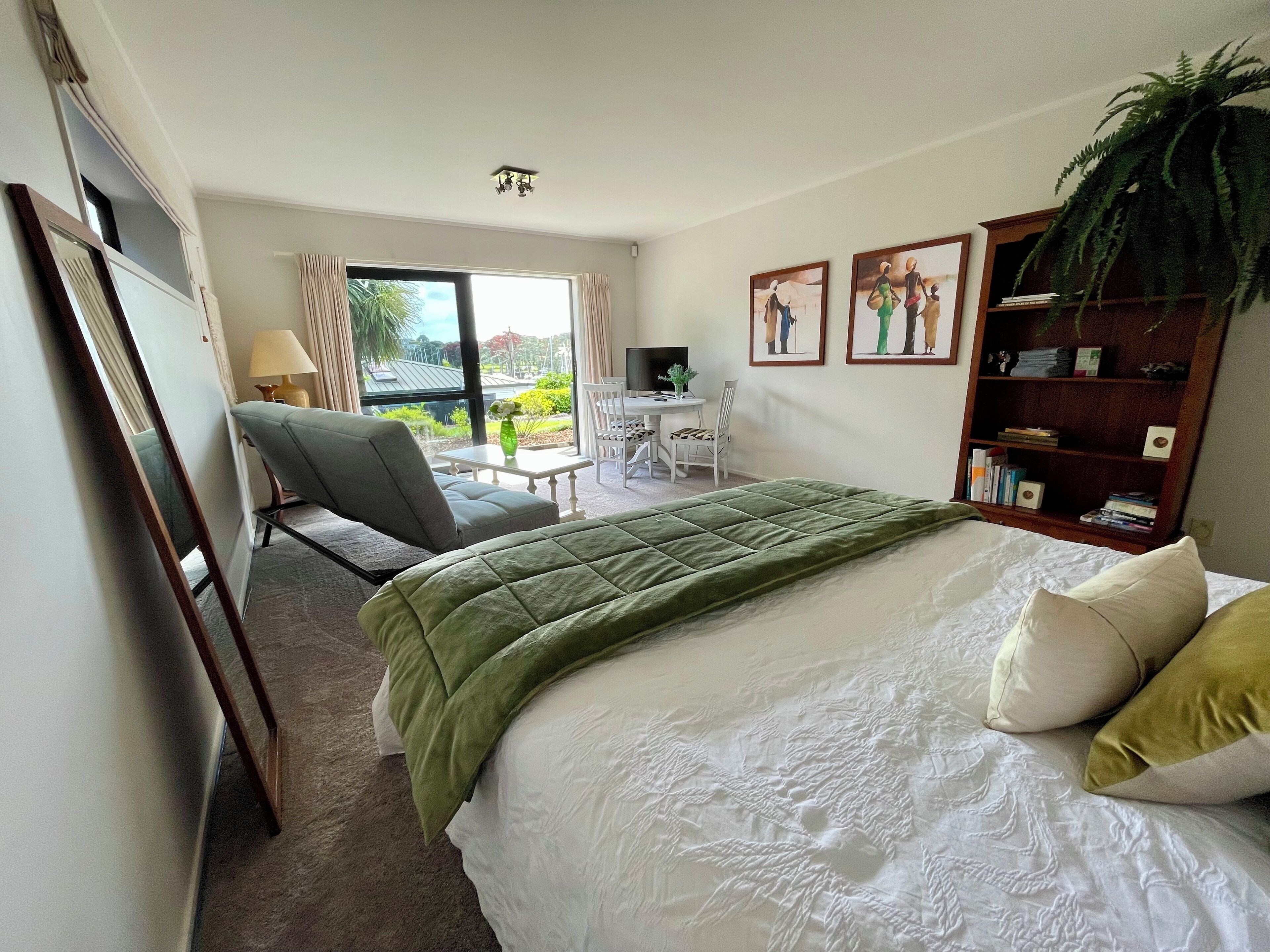 Una habitación de hotel con una cama, un escritorio, una silla, un televisor y una estantería.