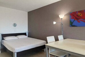 A hotel room with a bed, a table, and chairs. - PUZZLE - Studio Héliopolis L 86 - Classic - 4 people (AGDE)