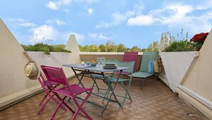 Eine Terrasse im Freien mit Tisch, Stühlen, einem Ventilator und Topfpflanzen.