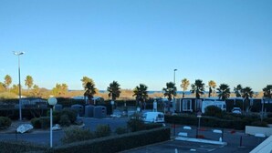 Ein Parkplatz mit markierten Stellplätzen, einem weißen Transporter und Wohnmobilen im Hintergrund.