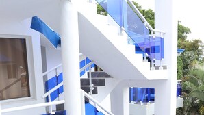Un edificio de varios niveles con barandillas de vidrio y elementos estructurales blancos.