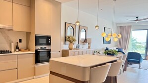 Cozinha moderna com eletrodomésticos integrados, uma ilha central com banquetas e uma área de refeições com vista.
