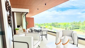 Uma área de estar moderna ao ar livre, com uma mesa e cadeiras brancas, teto de madeira e vista para uma paisagem exuberante.
