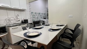 Una cocina moderna con armarios blancos, una mesa de comedor con platos y vasos, y una lámpara de techo circular original.