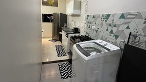 Una cocina compacta con lavadora y secadora integradas, un refrigerador y un lavamanos.