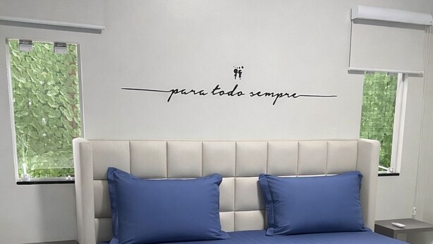 Un dormitorio con una cama, dos mesitas de noche y un equipo de aire acondicionado.