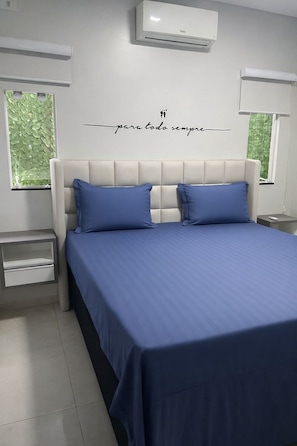 Ein Schlafzimmer mit einem Bett, zwei Nachttischen und einer Klimaanlage.