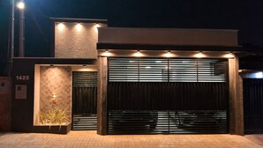 Un edificio moderno con un amplio portón de garaje, una pared con textura y una pequeña entrada con un accesorio de iluminación.