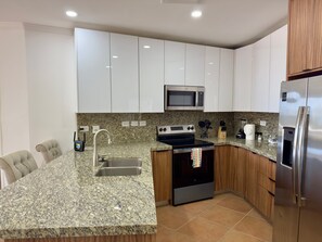 Eine moderne Küche mit weißen Schränken, einer Granit Arbeitsplatte, Edelstahlgeräten und einem eingebauten Backofen.