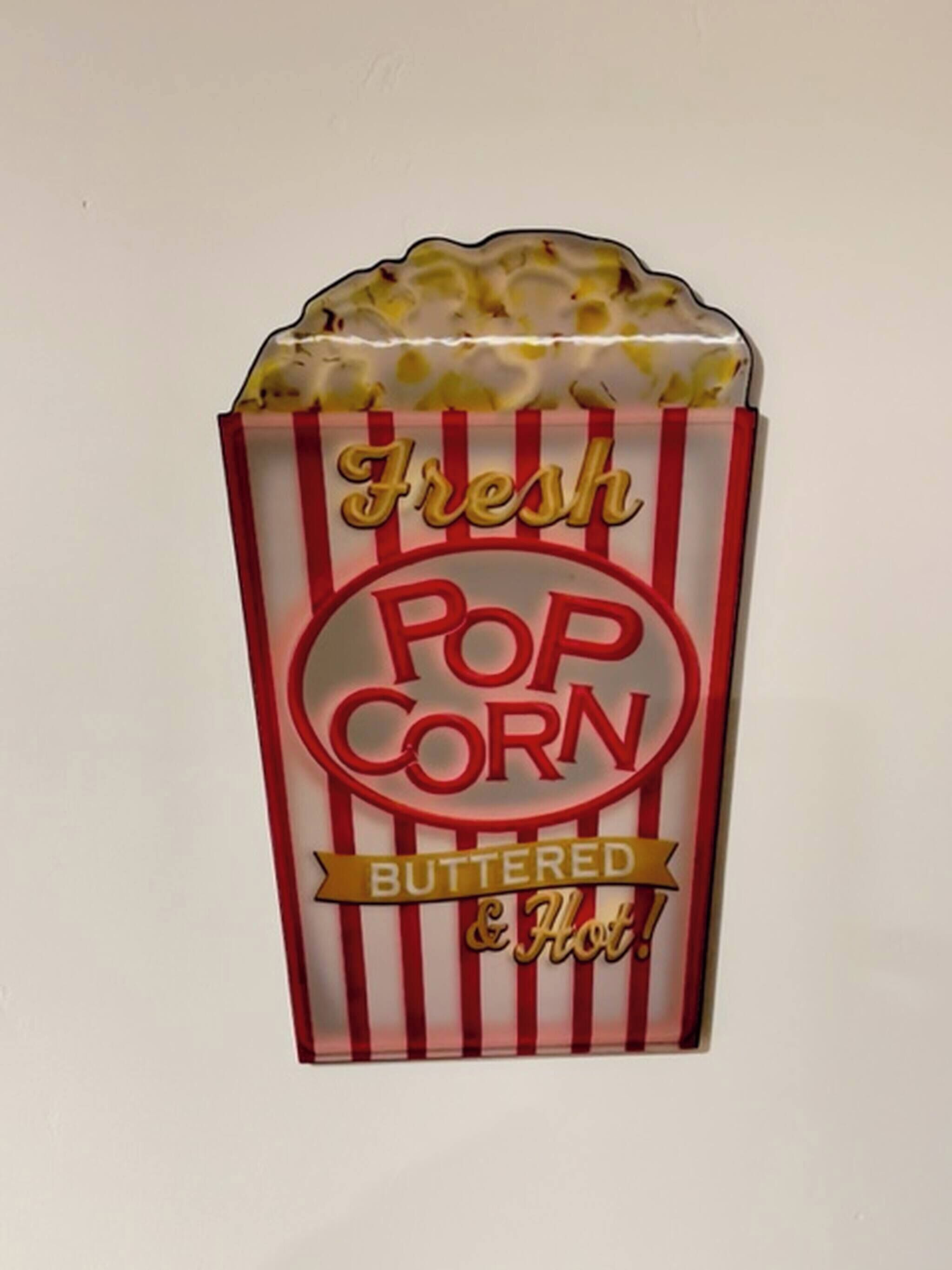 Una caja de palomitas de maíz con la inscripción "Fresh Popcorn Buttered & Hot!".
