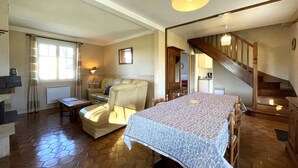 Ein gemütliches Zimmer mit einem Bett, einem Sessel, einem kleinen Tisch, einer Treppe und einem Fenster.