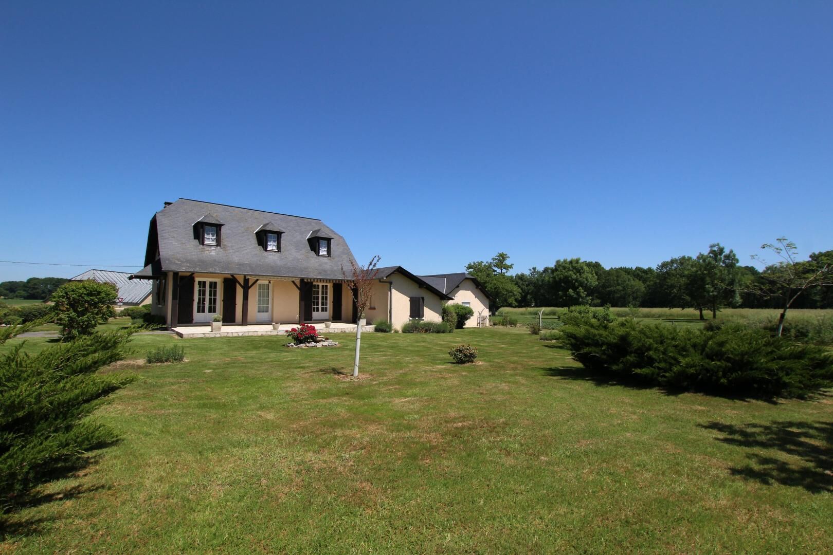 A two-story house with a sloped roof, a front porch, and a well-maintained lawn.