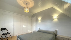 Ein Schlafzimmer mit einem Bett, Nachttischen, einem Sessel und einem Kleiderschrank.