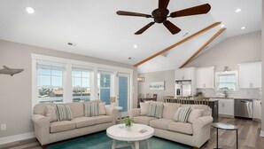 A spacious living room with two sofas, a coffee table, and a ceiling fan. - Rock Me on the Water: Oceanside, Pool, Hot Tub (Nags Head)