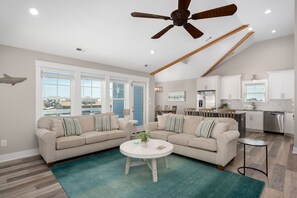 A spacious living room with two sofas, a coffee table, and a ceiling fan. - Rock Me on the Water: Oceanside, Pool, Hot Tub (Nags Head)