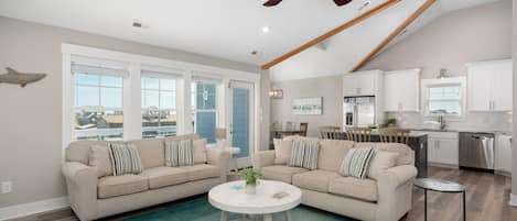 A spacious living room with two sofas, a coffee table, and a ceiling fan.