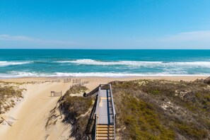 A beach with a wooden boardwalk leading to the shore, sandy beach, and ocean waves. - Rock Me on the Water: Oceanside, Pool, Hot Tub (Nags Head)