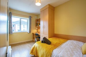 Ein Schlafzimmer mit einem Bett, einem Schreibtisch und einem Kleiderschrank.
