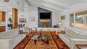 Un salon moderne avec une cheminée, deux canapés, une table basse et une grande fenêtre.