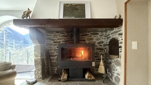 Ein Steinkamin mit Feuer, ein gerahmtes Bild darüber und eine Steinsitzbank links.