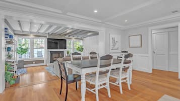 A dining area with a wooden table and chairs, a fireplace, and a view of the outdoors.