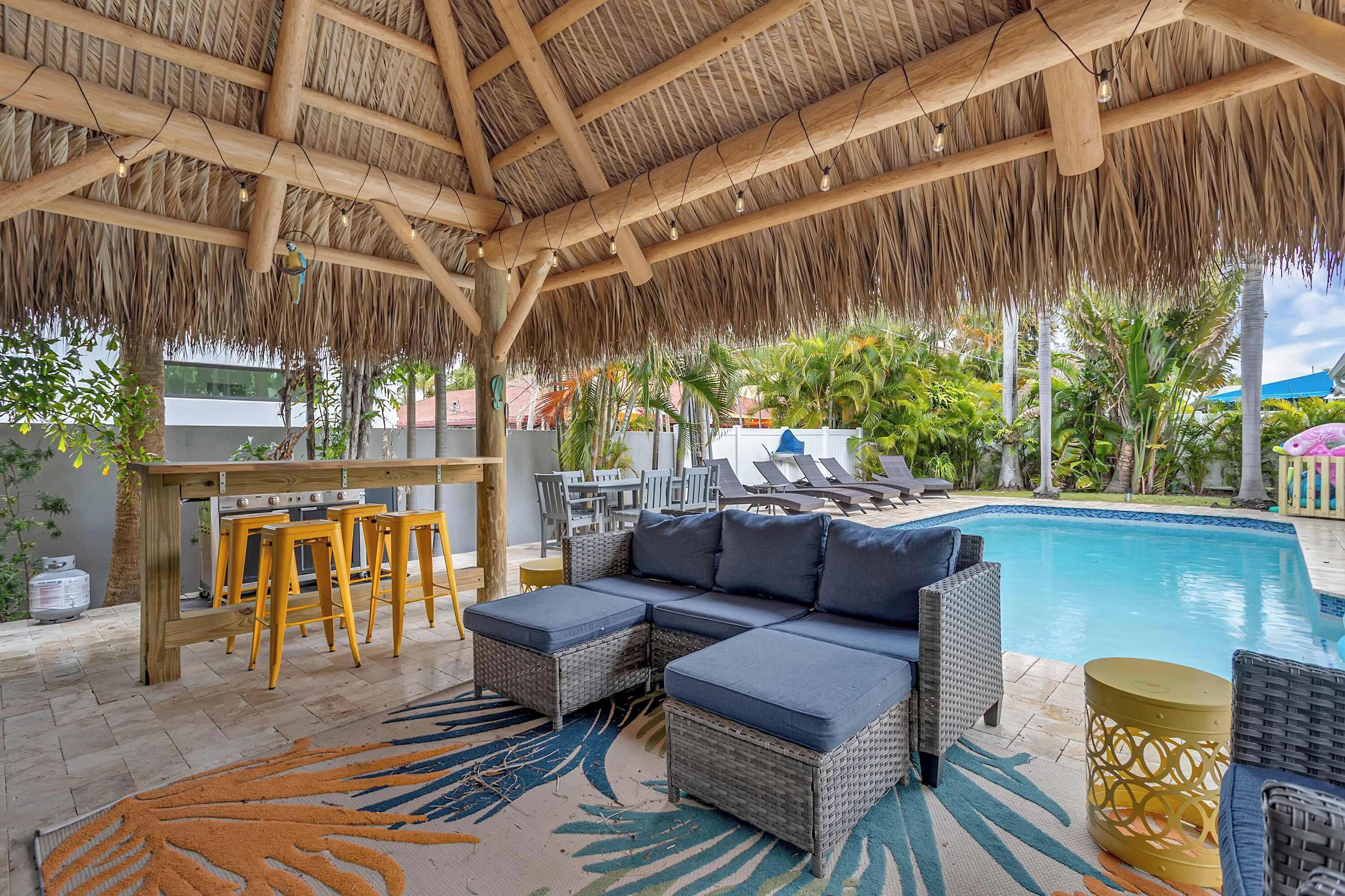 A covered outdoor area with a pool, wicker furniture, and a bar.