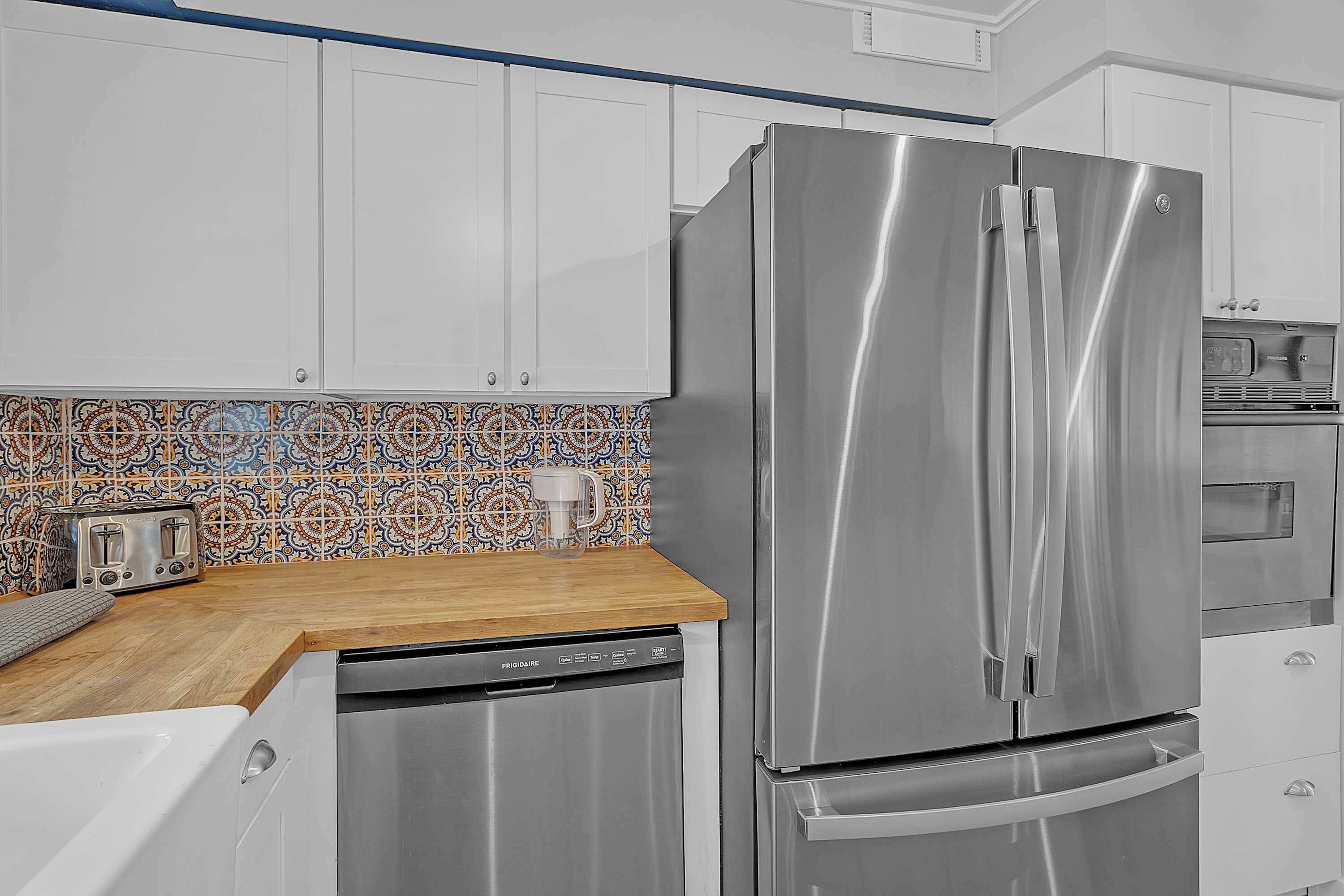 A modern kitchen with stainless steel appliances, a dishwasher, and a patterned backsplash.